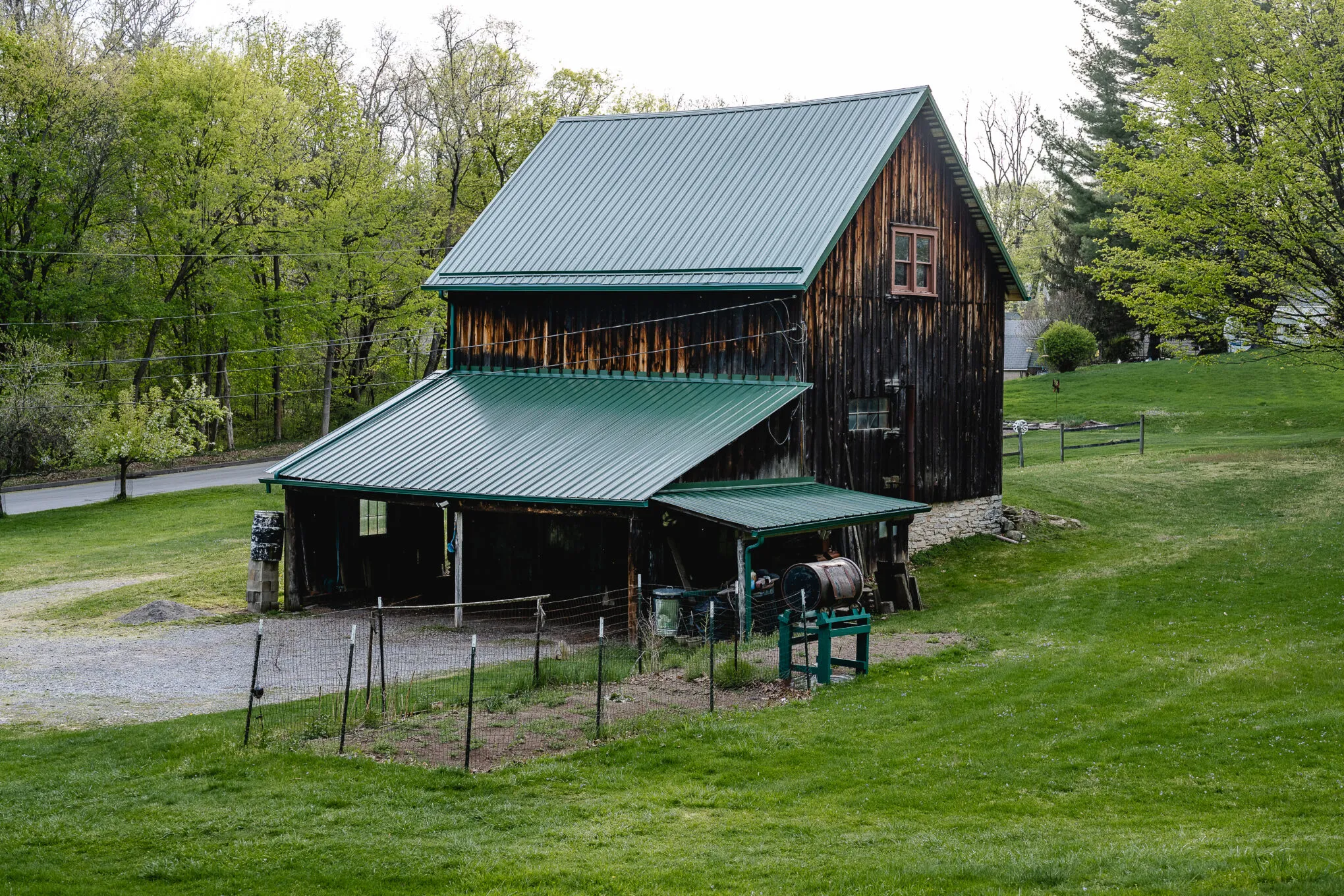 An older wooden barn with a new green metal roof and an attached lean-to