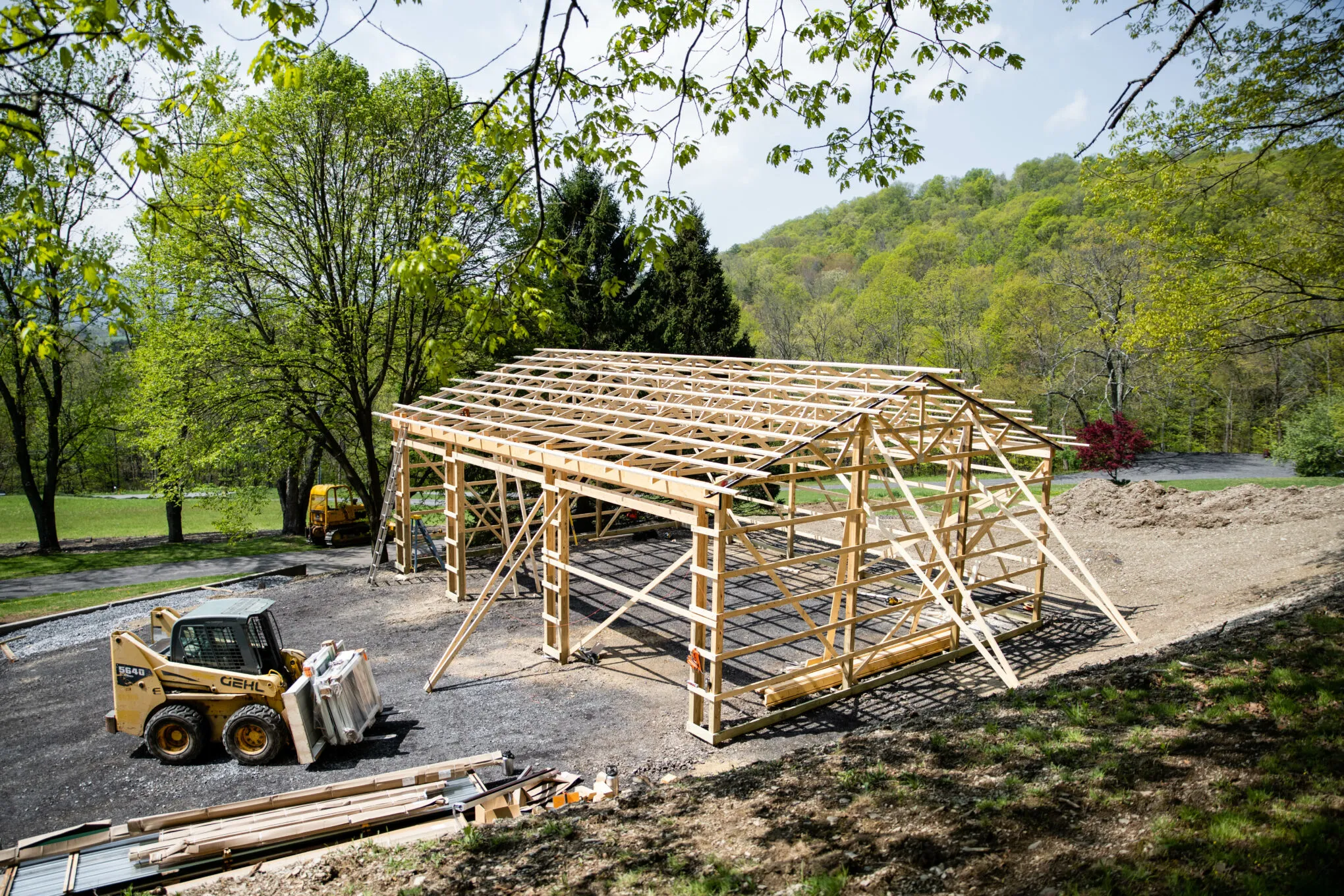A post-frame building under construction, with the posts set and the roof trusses going up