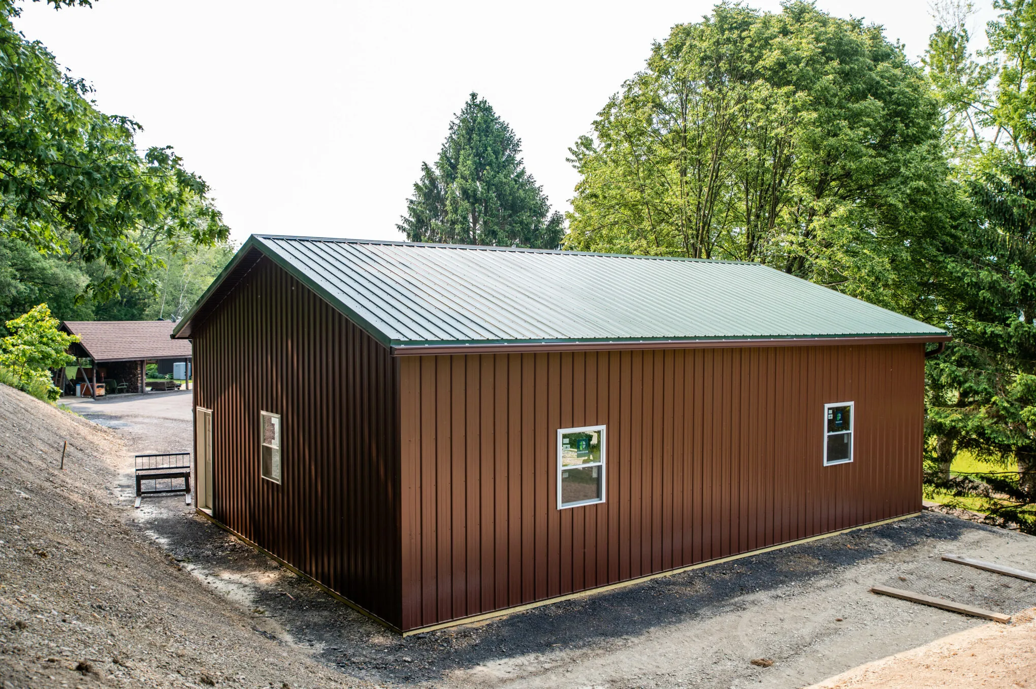 A brown post-frame outbuilding with a green metal roof